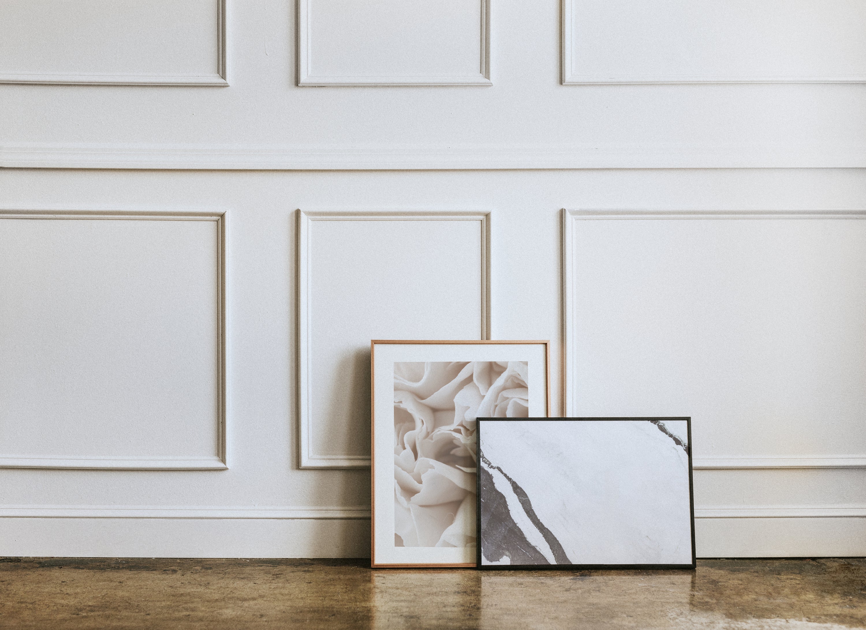 two framed prints sitting against wall