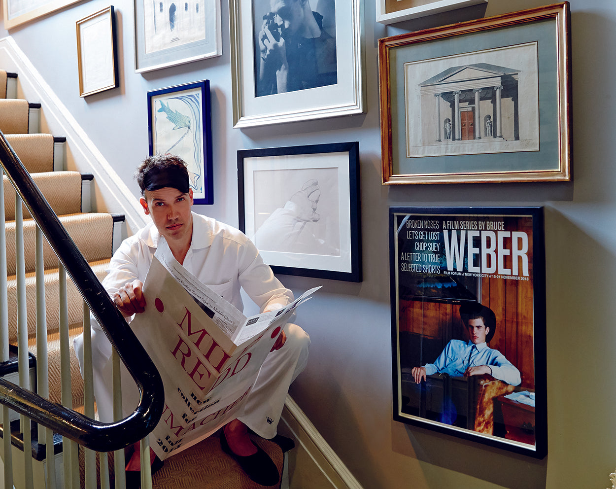 photo of Miles Redd sitting on stairs next to many skyframe framed photographs and prints