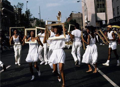 women wearing white dancing in the street using gold frames as props