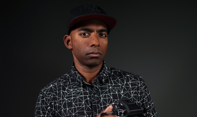 photo of Dinesh Boaz wearing black hat and geometric shirt