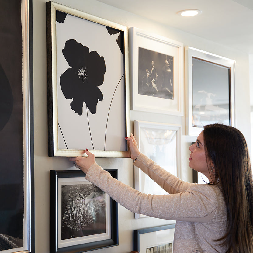 interior designer hanging picture frame on wall with original artwork made by skyframe in high end apartment