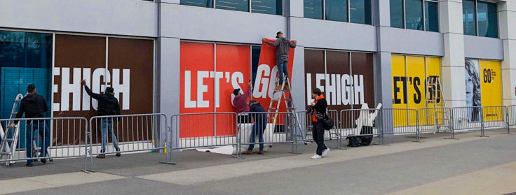 installers hanging up custom colourful decal banners for store windows