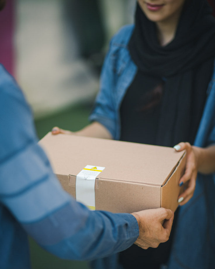 person handing off box to another individual wearing blue shirts