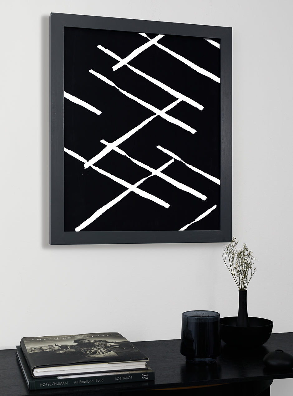 grey frame holding abstract art hung above table with various objects