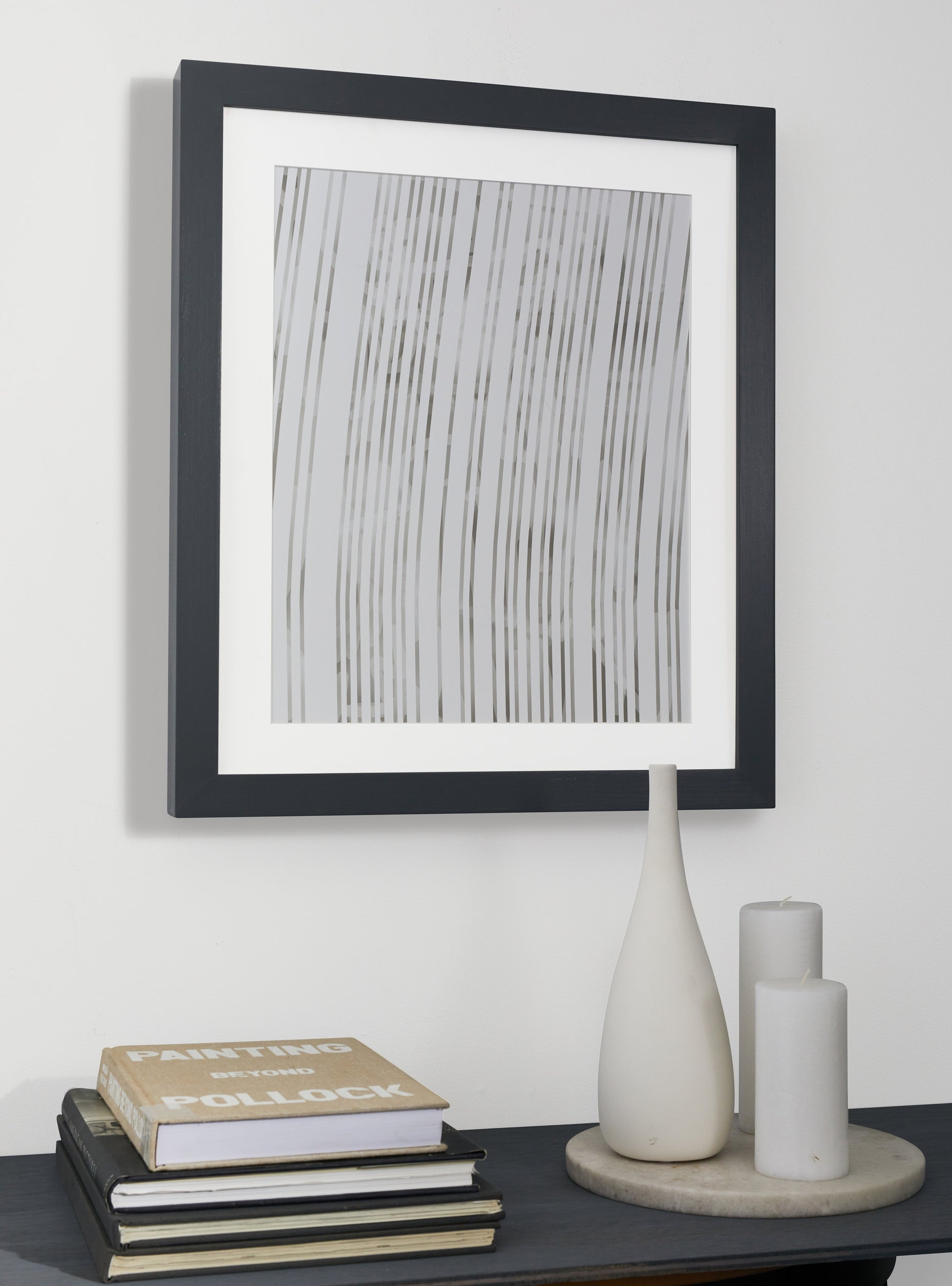 Photograph of a frame in a home with a table underneath showing various items