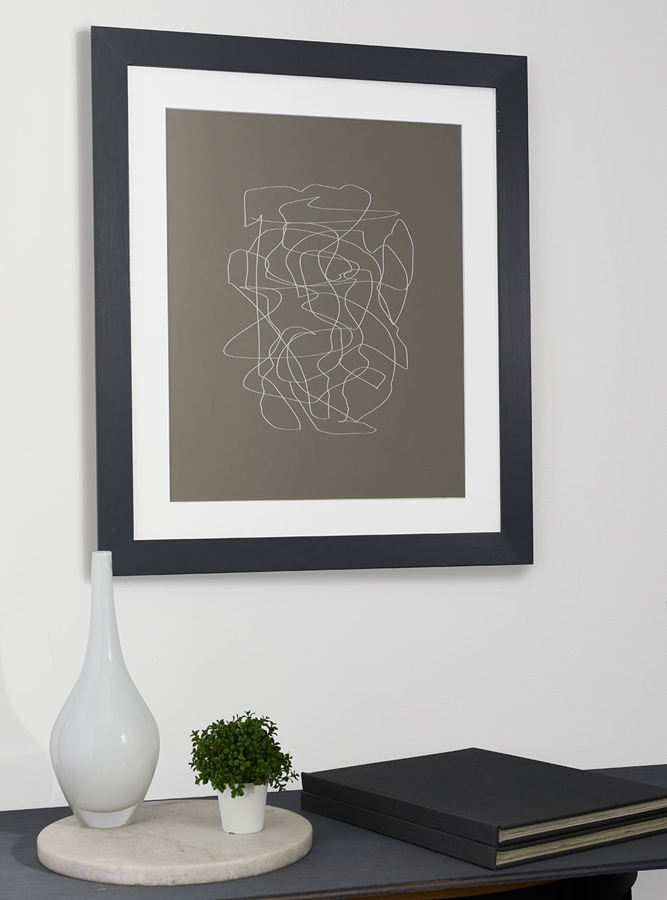 grey frame holding abstract art hung above table with various objects