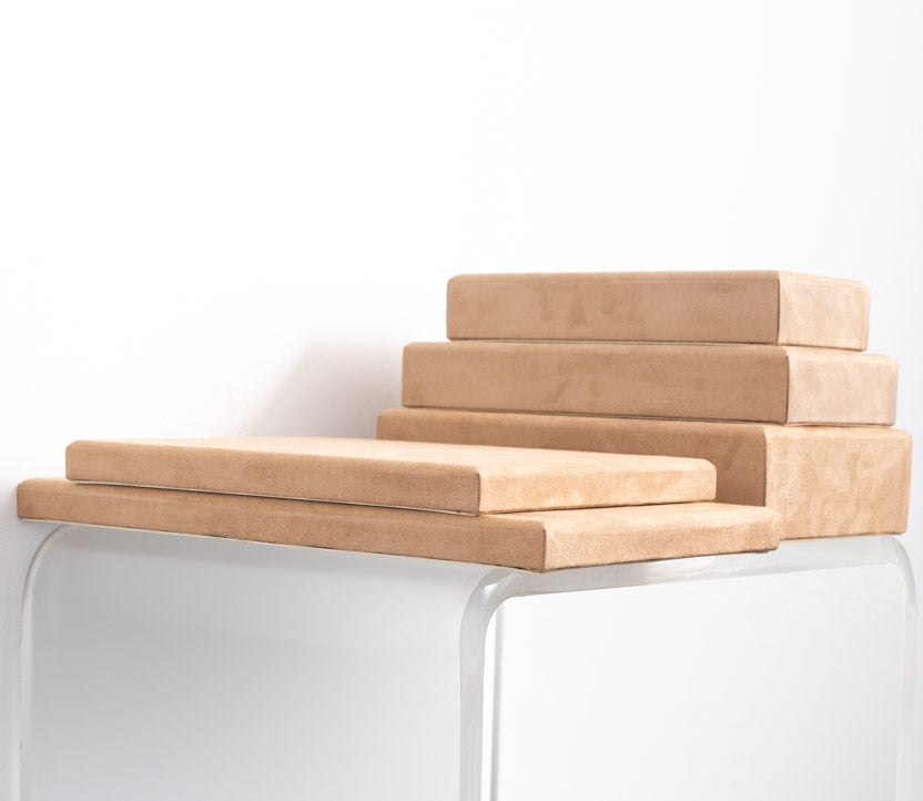 stack of risers covered in tan suede material made for retail store displays