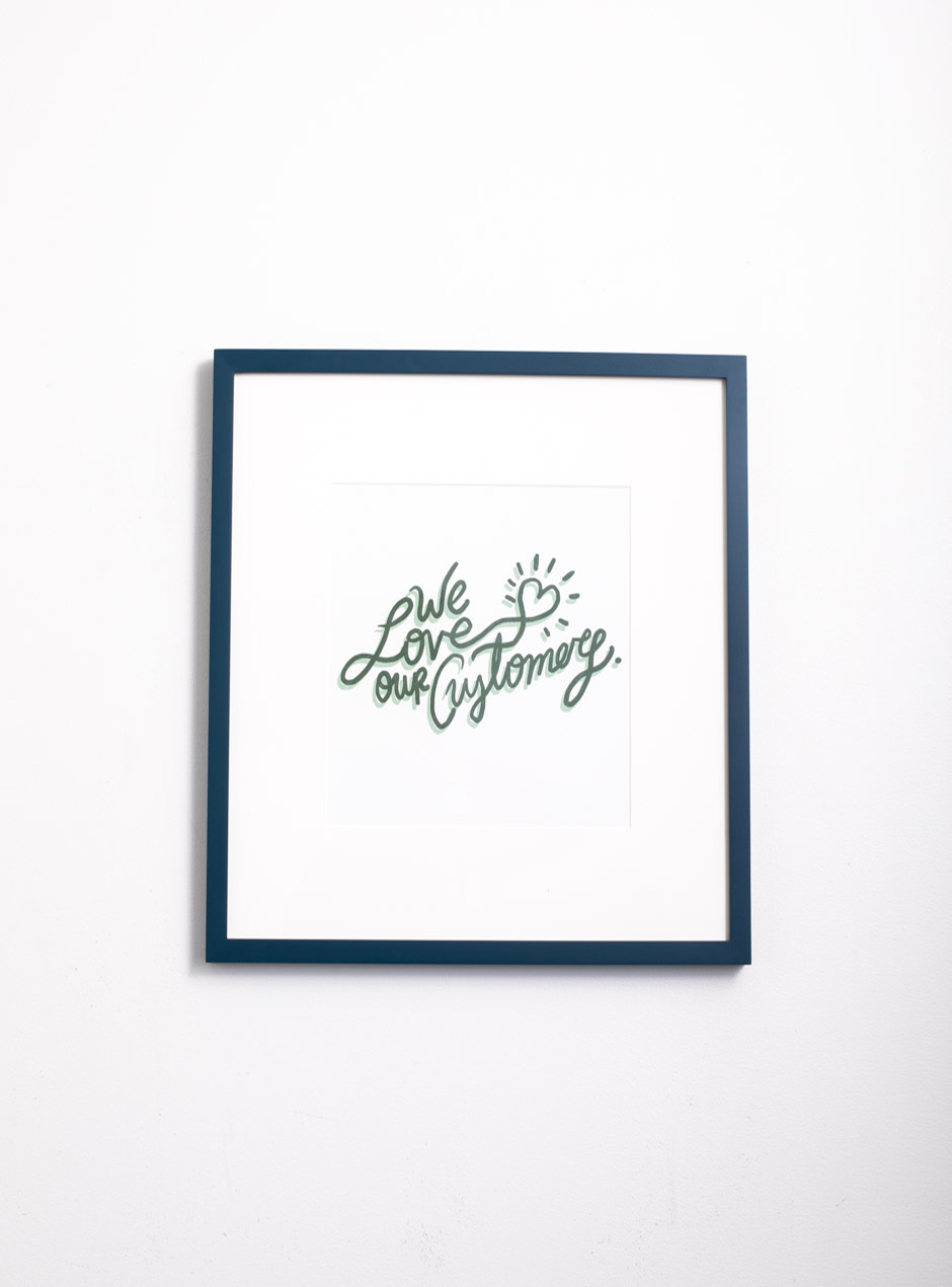 we love our customers in green writing in thin navy frame