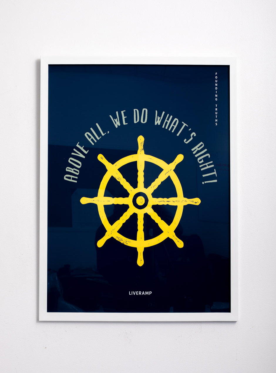 dark navy print that says above all, we do what's right! above a yellow boat wheel in a white high quality frame.