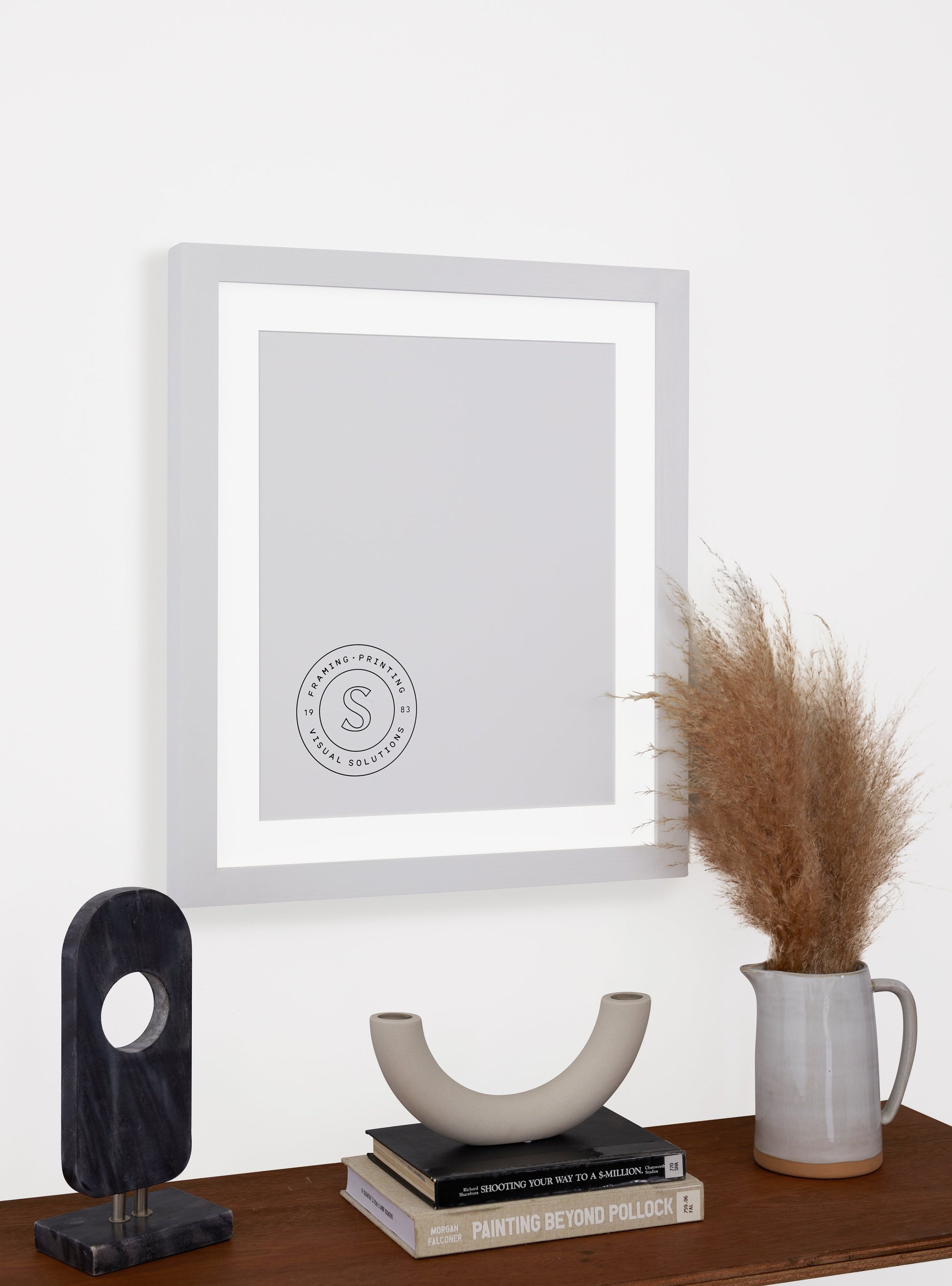Photograph of a frame in a home with a table underneath showing various items