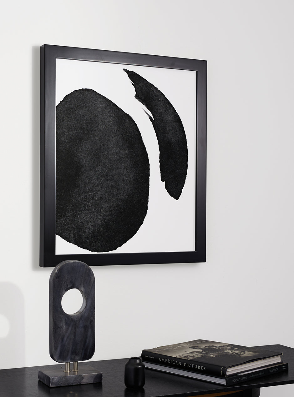 black frame with abstract art hung above table with various objects 