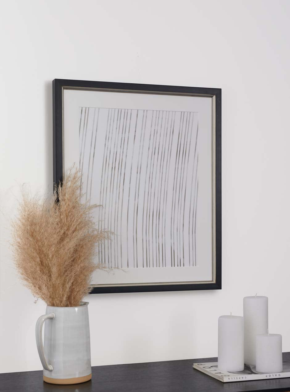 black frame with silver inner detailing hung above table with various objects 