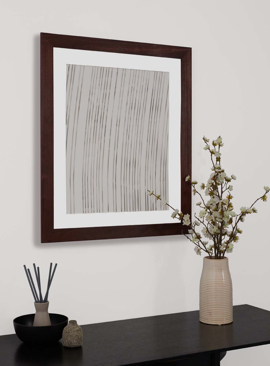 dark stained wooden frame holding abstract painting hung above table with various small objects
