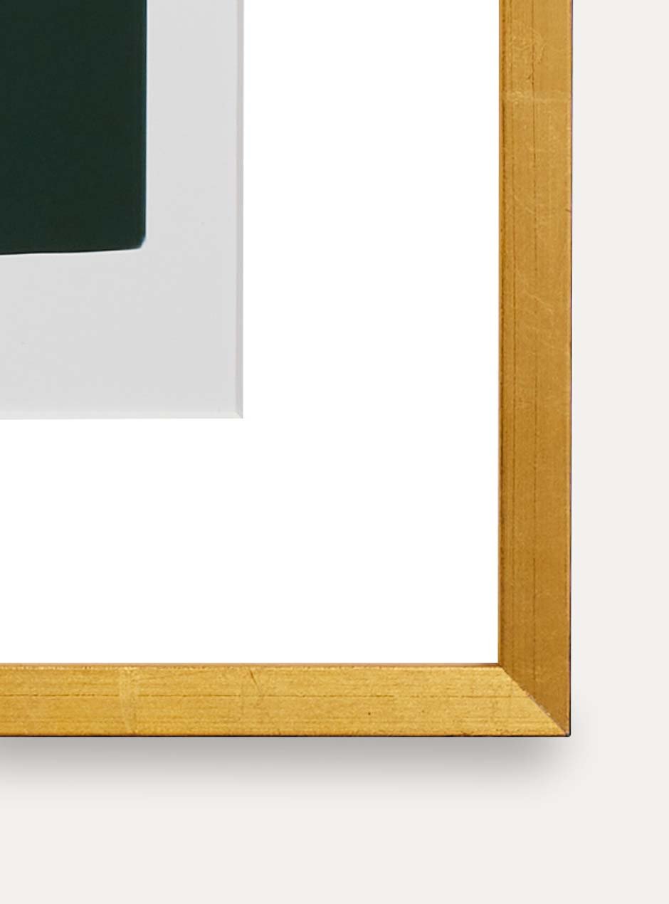 detailed photo of shiny yellow gold leafed high end frame with white mat border and green artwork resembling stones.