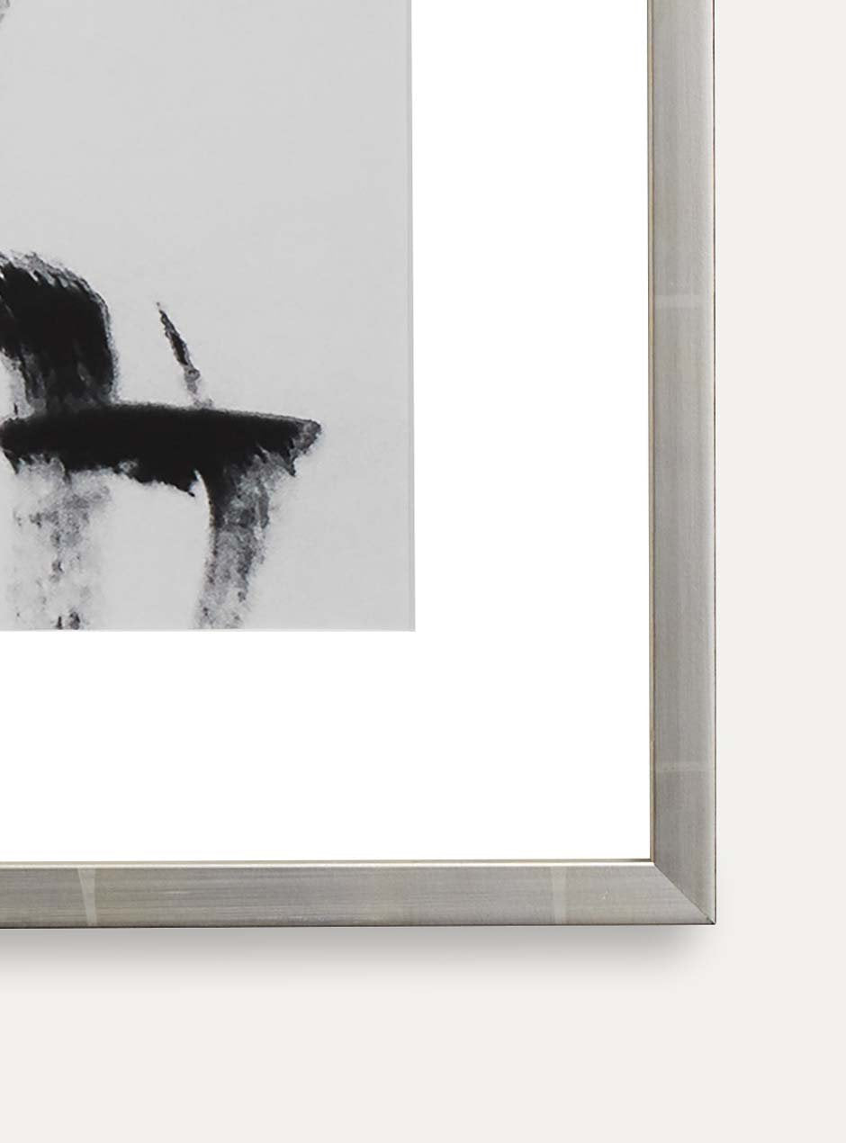 detail photo showing joining of reflective metallic silver thin frame with various lines across moulding shown with white mat and an abstract ink line art piece