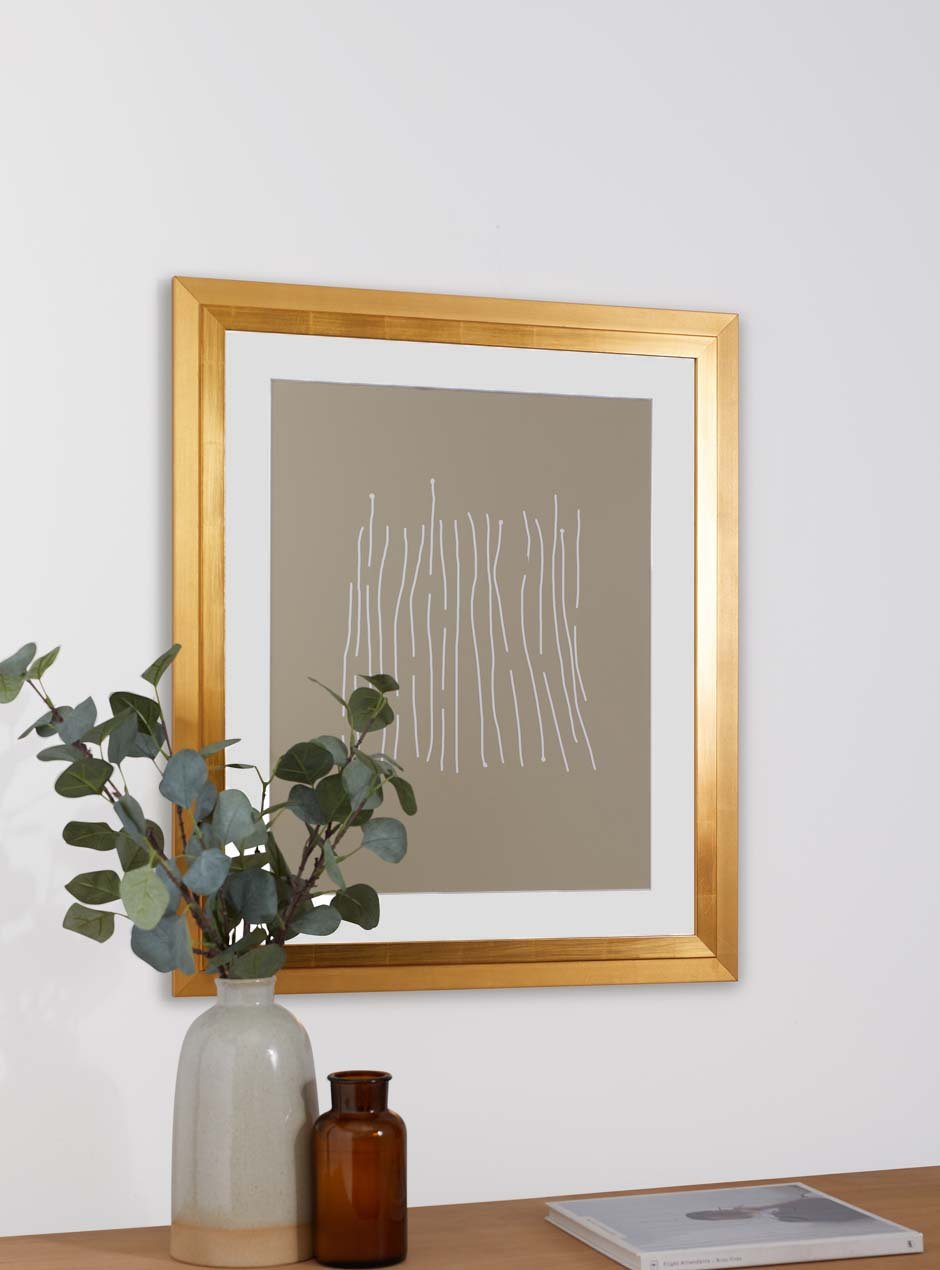 gold frame holding abstract art hung above table with various objects