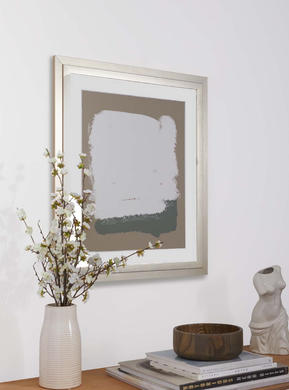 silver frame holding abstract art hung above table with various objects