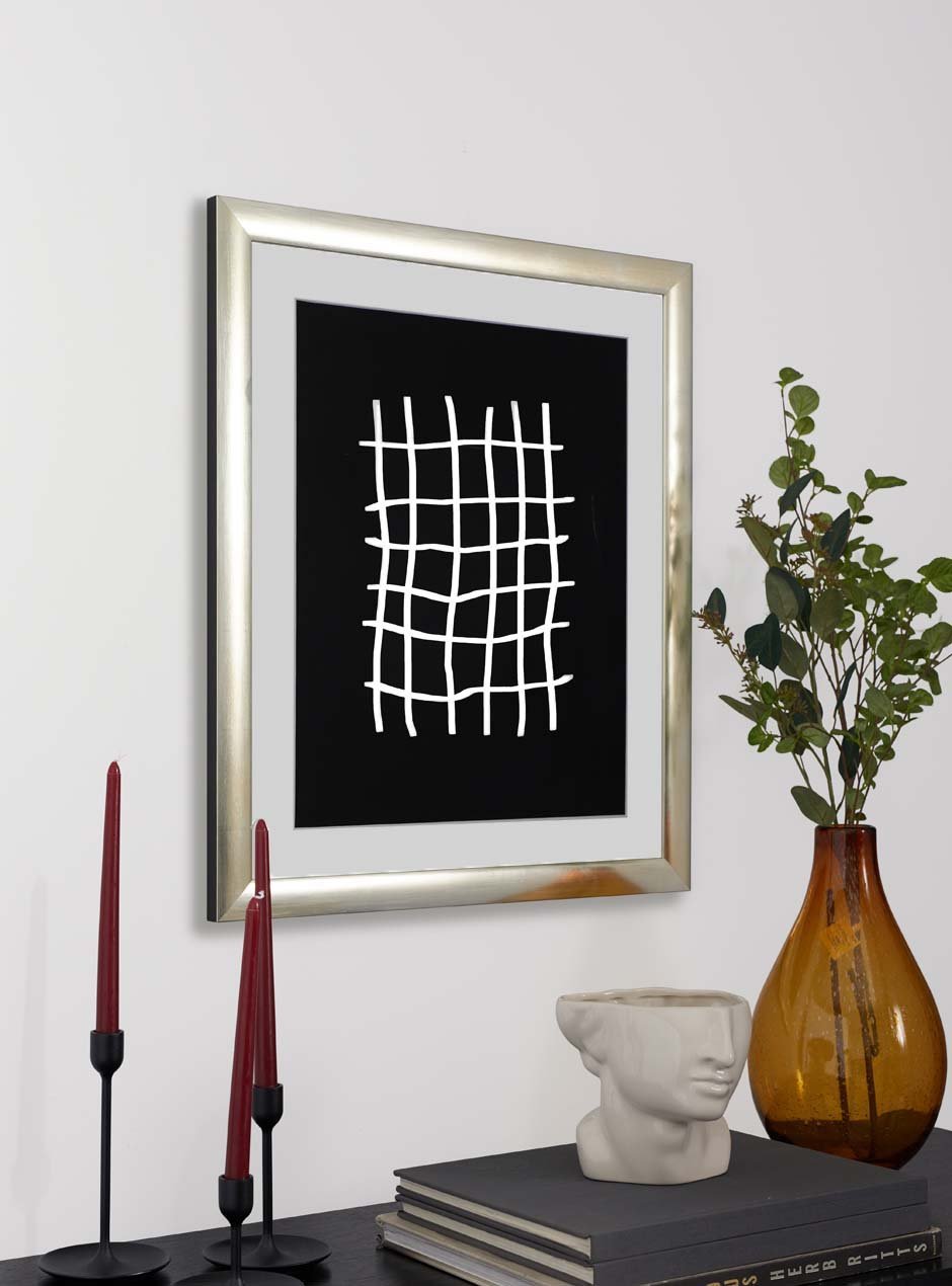 silver frame holding abstract art hung above table with various objects