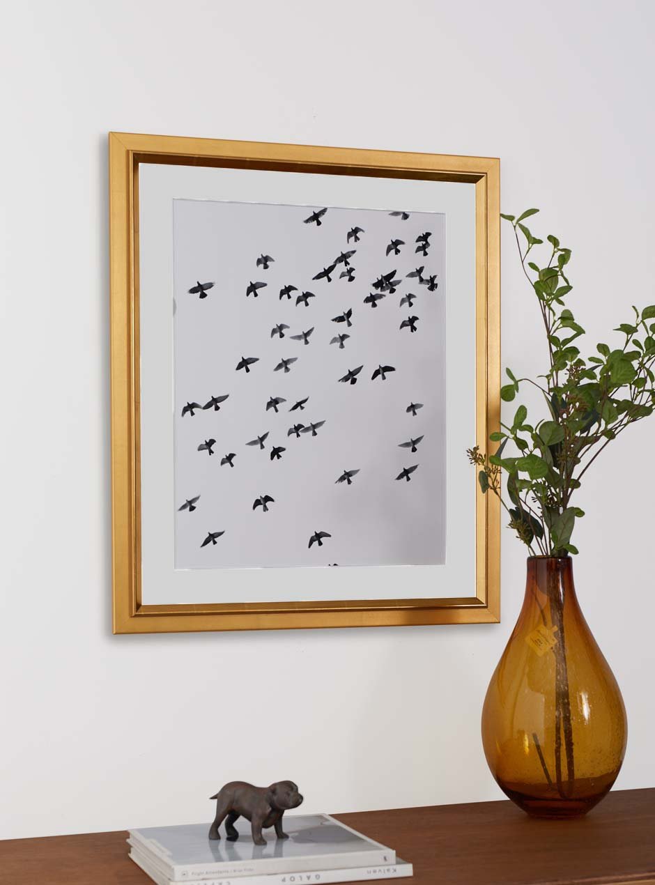 gold frame holding abstract art hung above table with various objects