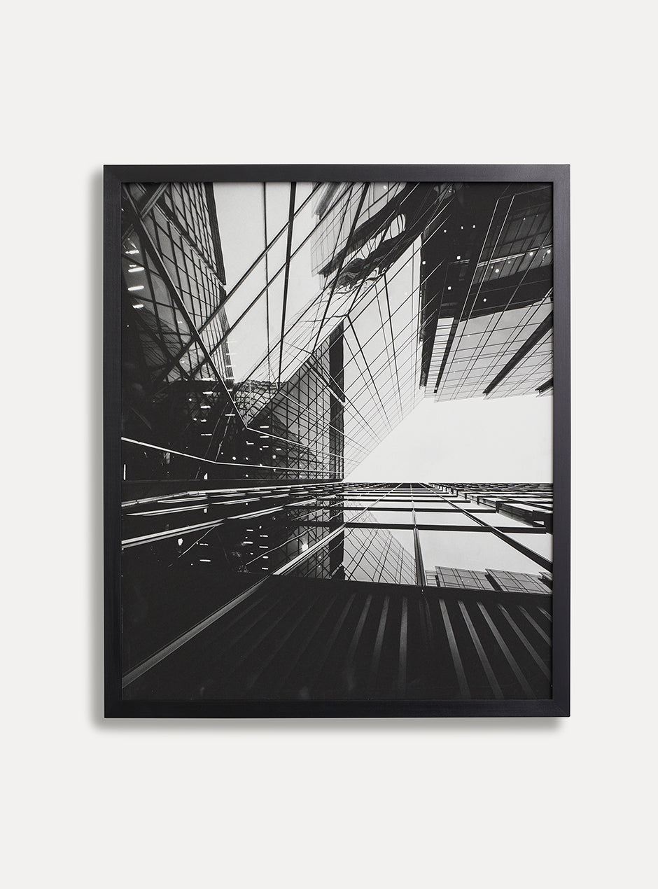 black and white print of buildings in the city in black frame on white wall