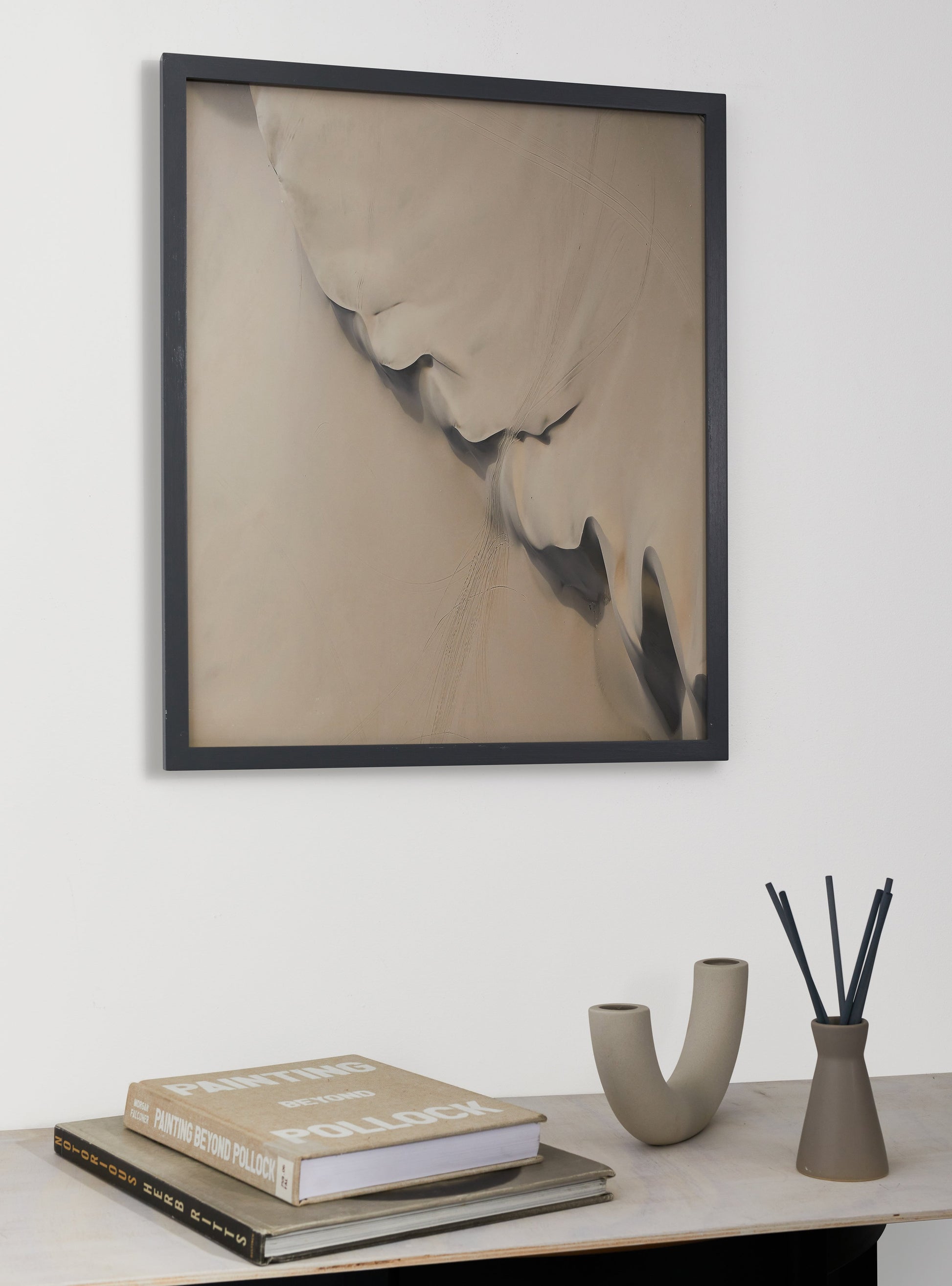 Photograph of a frame in a home with a table underneath showing various items