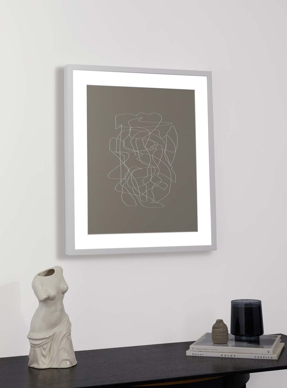 white  frame holding abstract art hung above table with various objects 