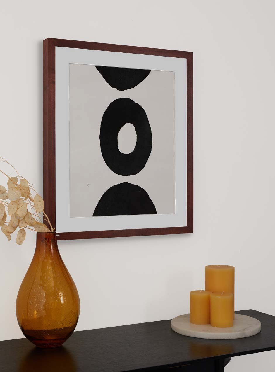 maple wooden frame with abstract circle image inside hung above table with assorted candles