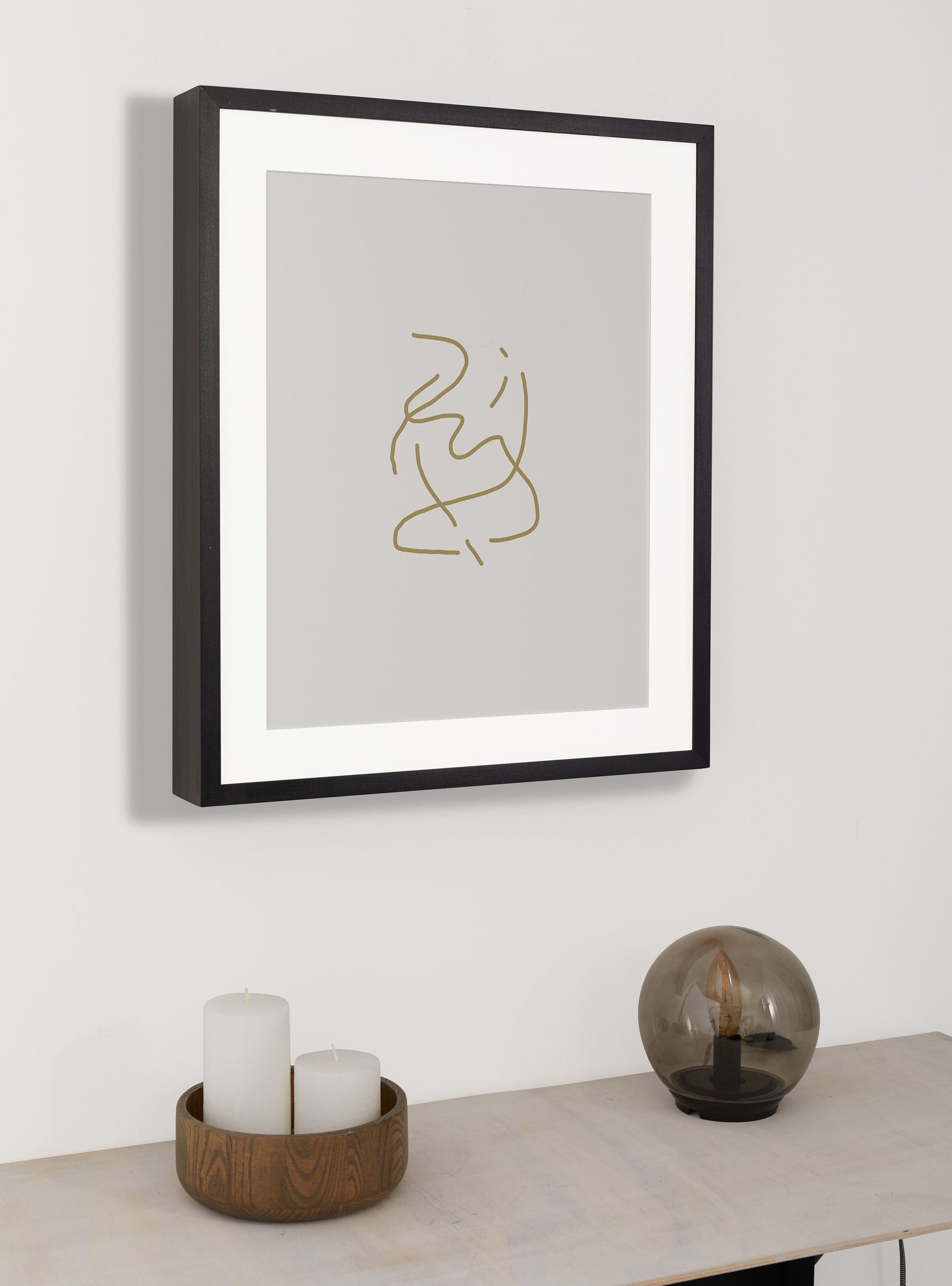 Photograph of a frame in a home with a table underneath showing various items