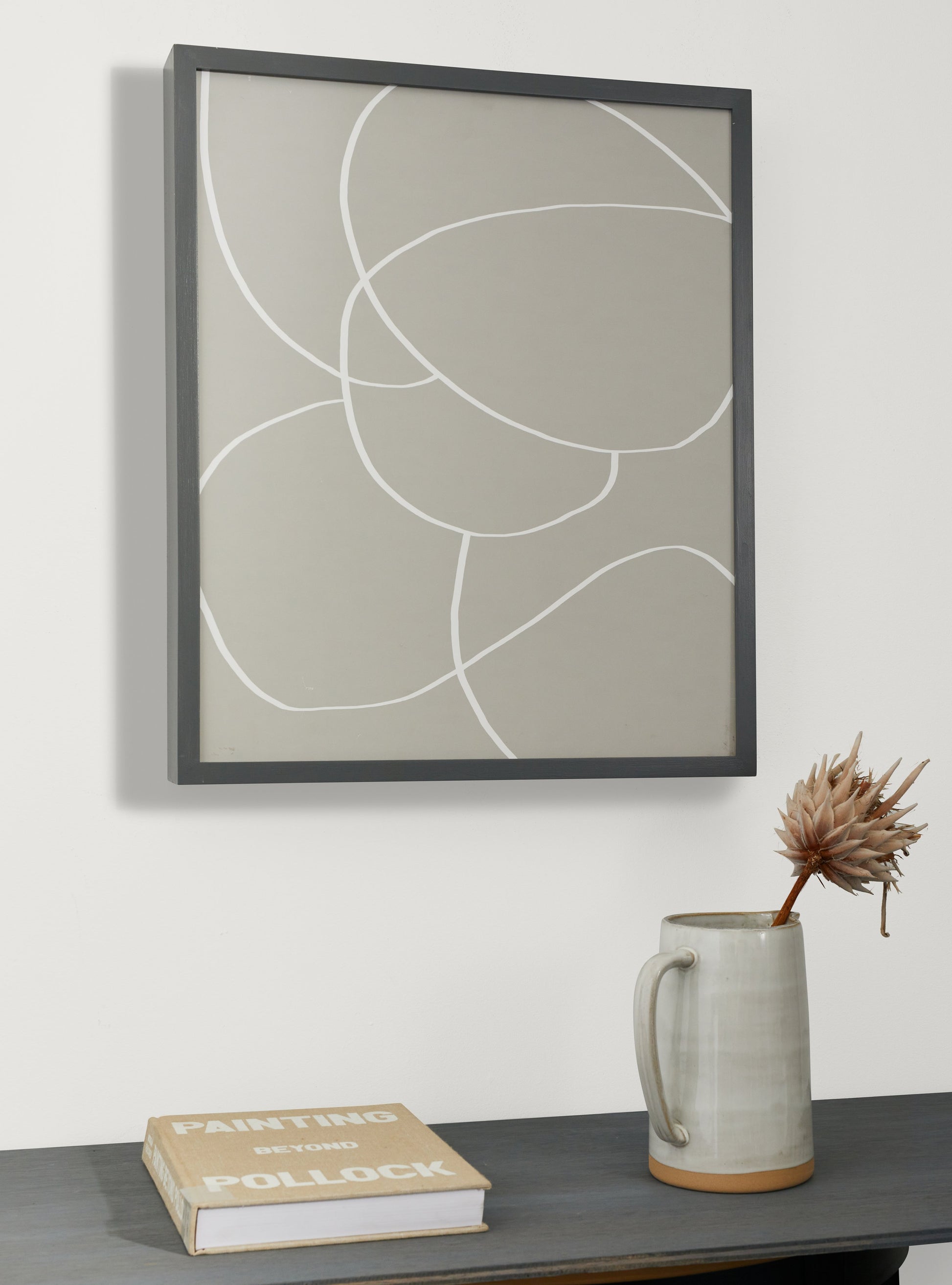 Photograph of a frame in a home with a table underneath showing various items