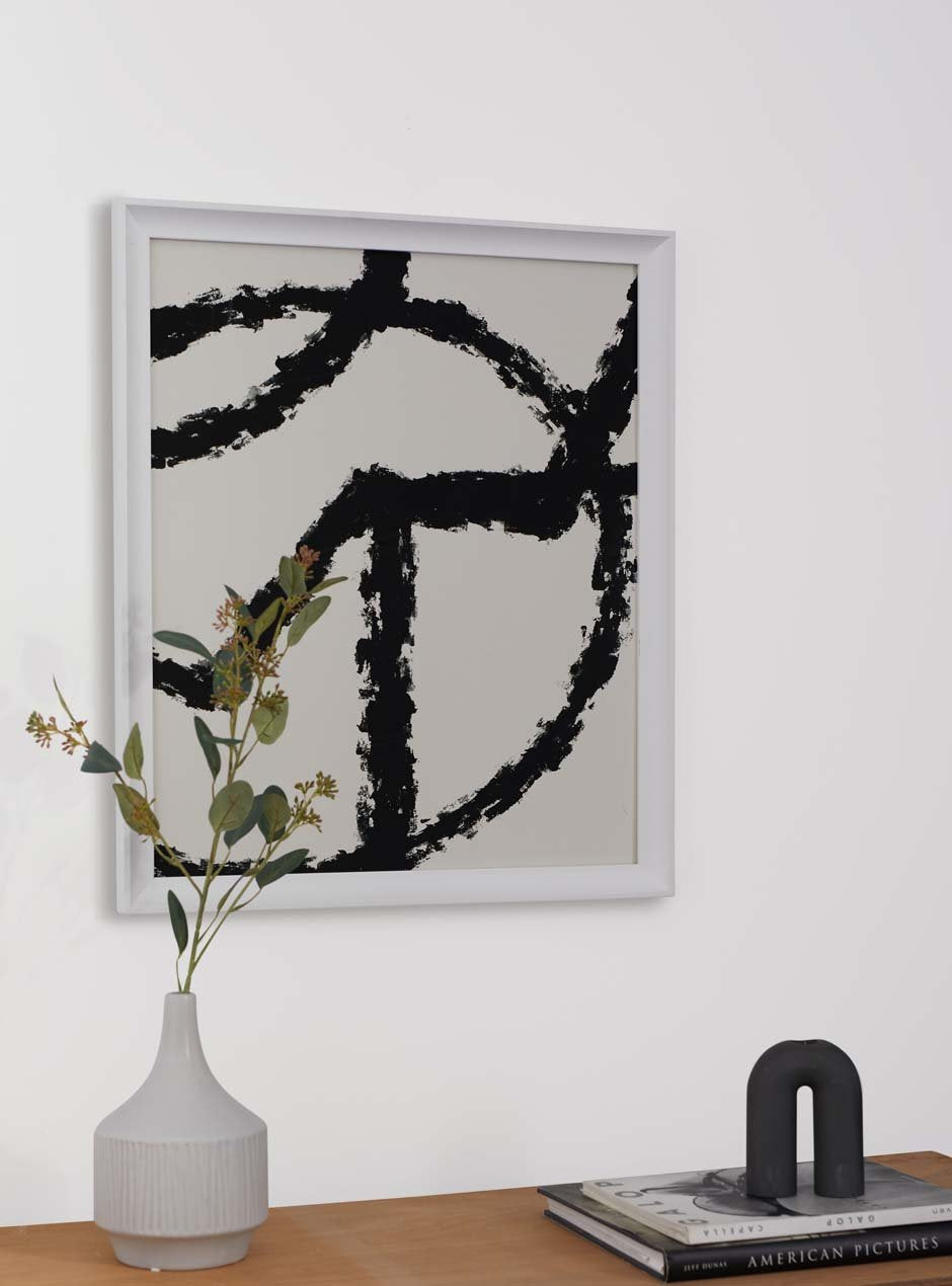 white frame holding abstract art hung above table with various objects