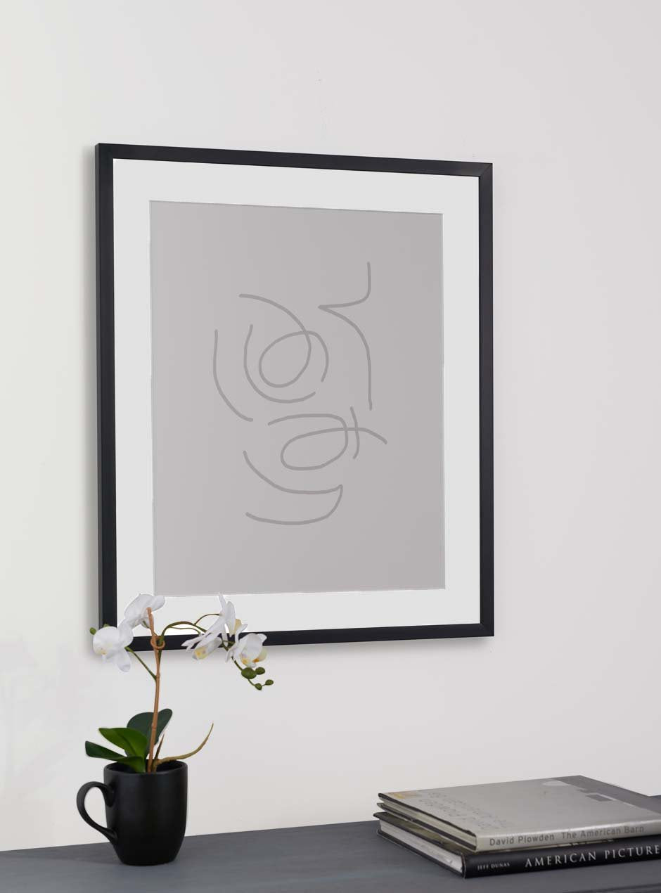 thin black frame holding abstract art hung above table with various objects
