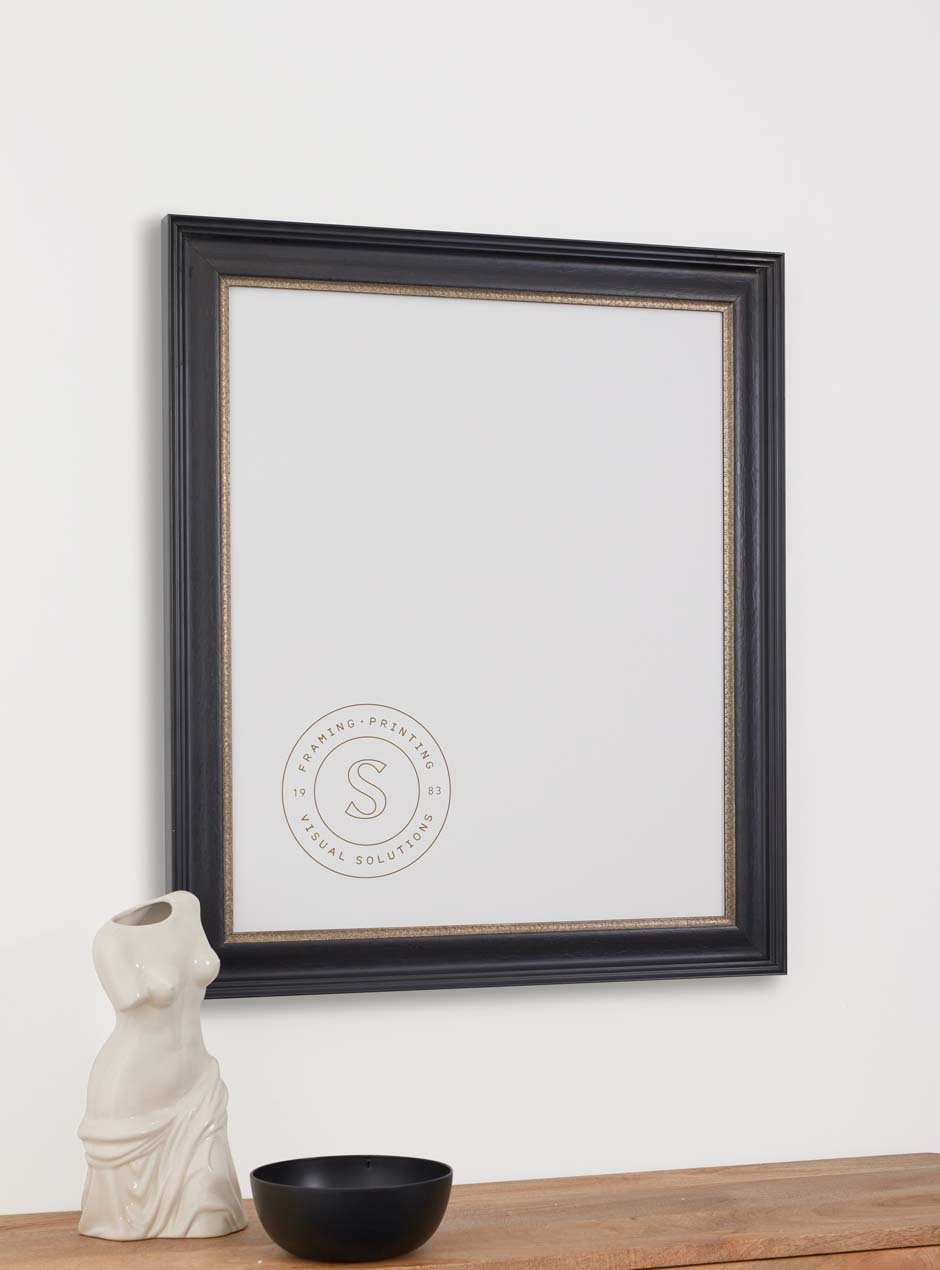 black frame with gold inner detailing hung above table with various small objects