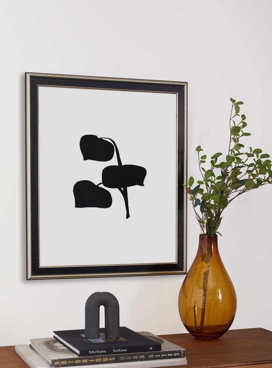 black frame with silver inner and outer detailing hung above table with various objects