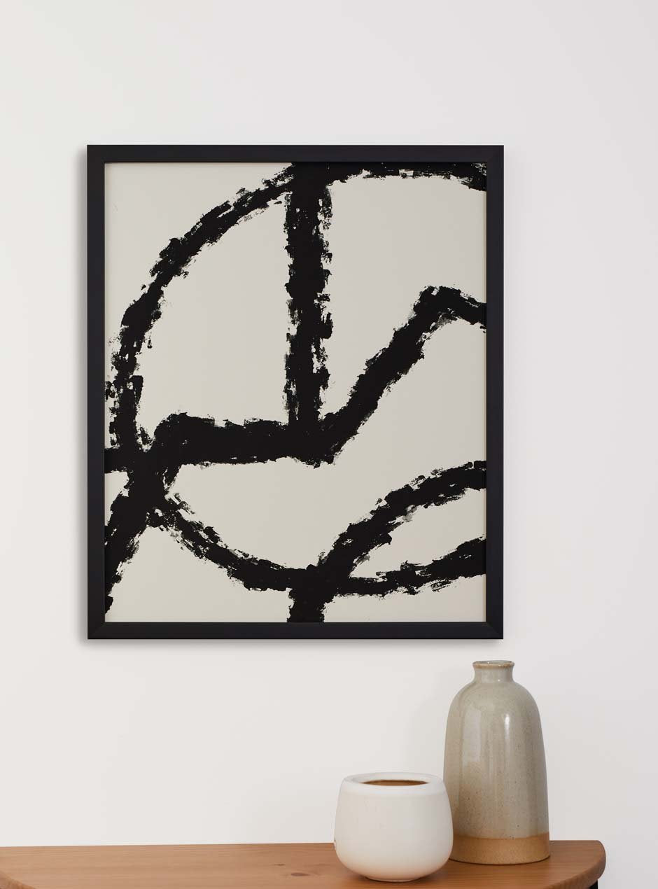 black frame holding abstract art hung above table with various objects