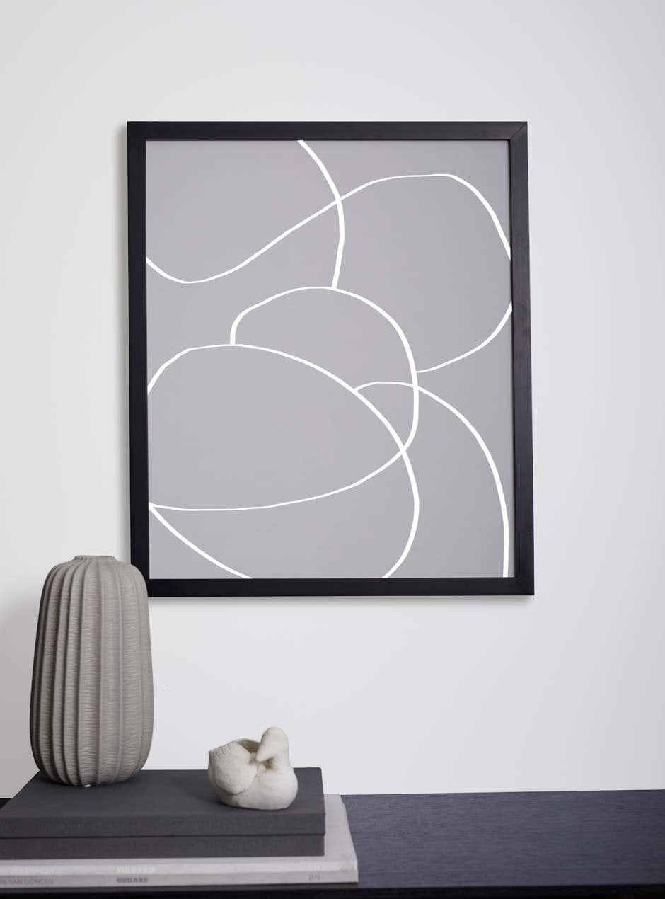 thin black frame holding abstract art above table with various objects 